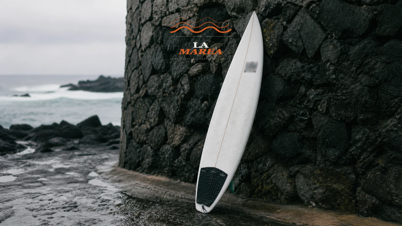 La Marea board nose decal against volcanic stone wall
